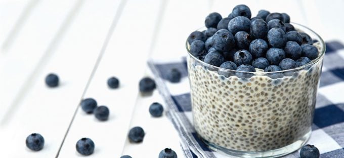 Chia Seed pudding with buleberries in a glass cup on a white wooden table with blueberries on the table